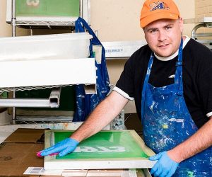 a young man working in a silk screen shop